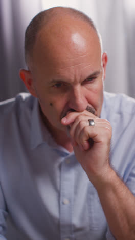 Vertical-Video-Close-Up-Of-Depressed-Mature-Man-Struggling-With-Mental-Health-Sitting-In-Thought